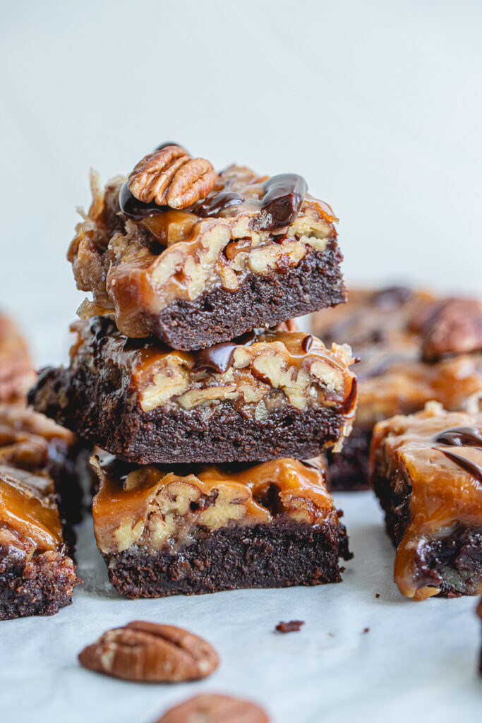 A perfectly sliced Pecan Caramel Brownie Bar, viewed from the side, ready to be served as a holiday dessert.