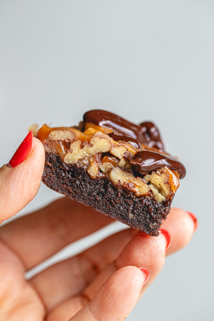 Cross-section of a Turtle Brownie Bar, highlighting the rich fudgy bottom layer and the thick, gooey salted caramel pecan topping.
