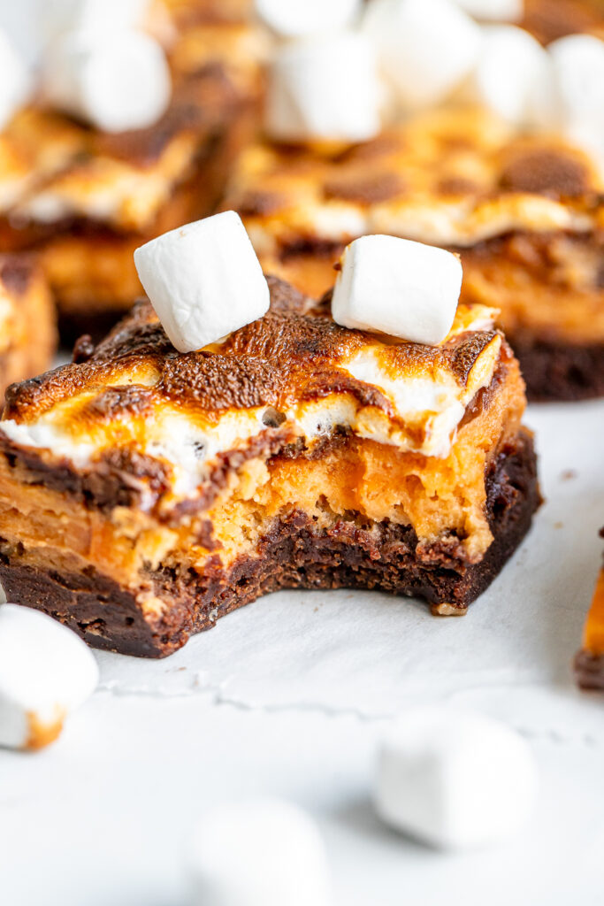 Close-up of a sliced Sweet Potato Brownie Bar, showing the distinct fudgy chocolate base, creamy orange sweet potato layer, and fluffy toasted marshmallow topping.