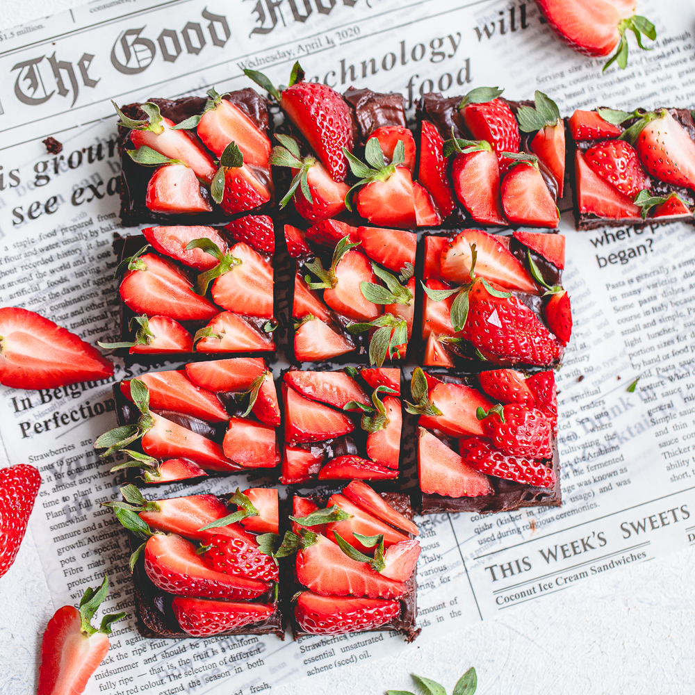 Sliced squares of rich chocolate brownies layered with glossy ganache and loaded with fresh strawberries.